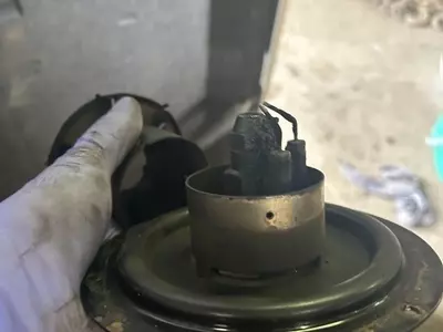 Close-up of heavily carboned burner nozzle and electrodes before servicing on a Nilfisk SH Truck Booster, showing soot build-up affecting combustion.
